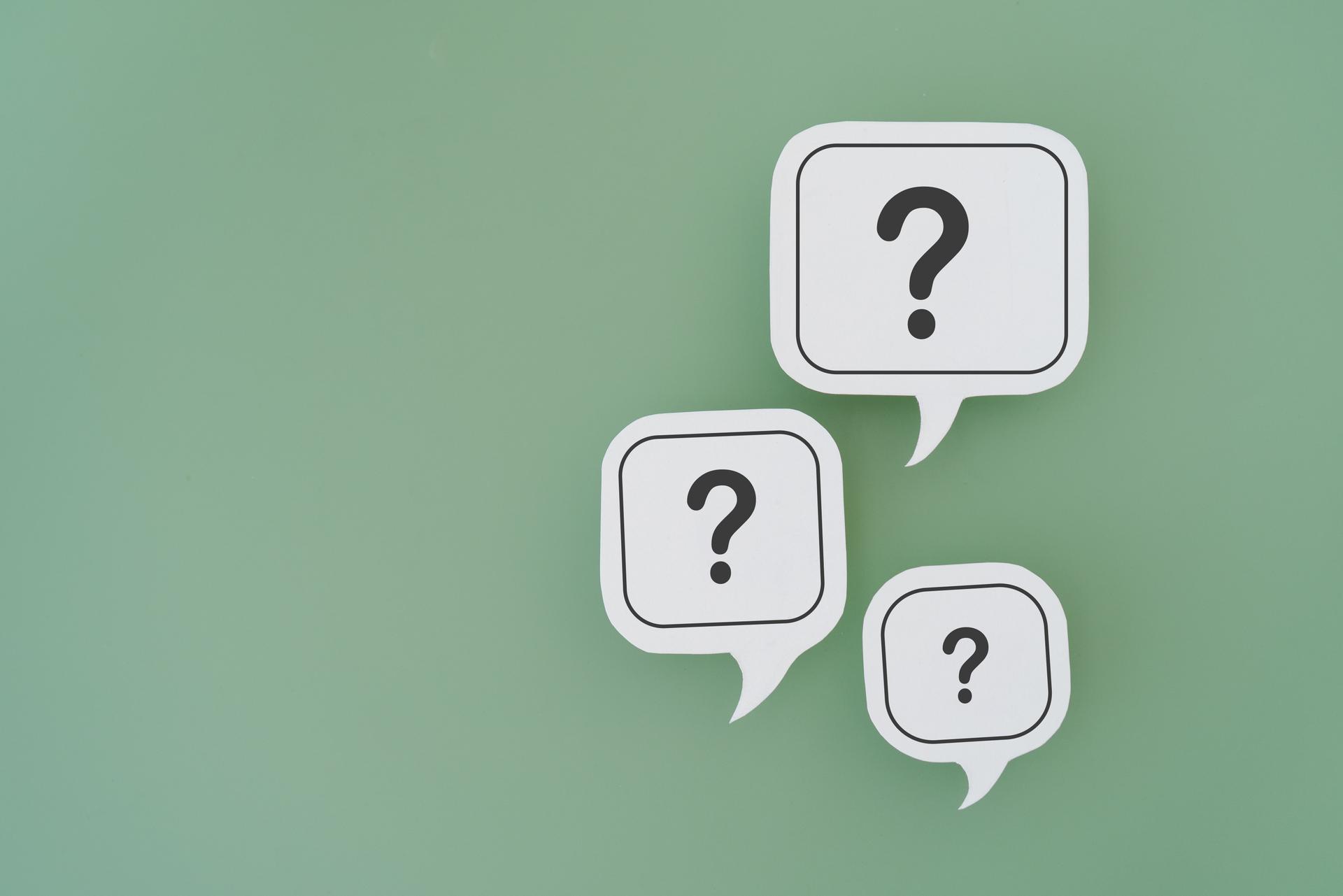 For FAQ , Frequently asked questions concept, asked questions  and answers. Question mark on  different size of white speech bubble real paper cut on green background, copy space included