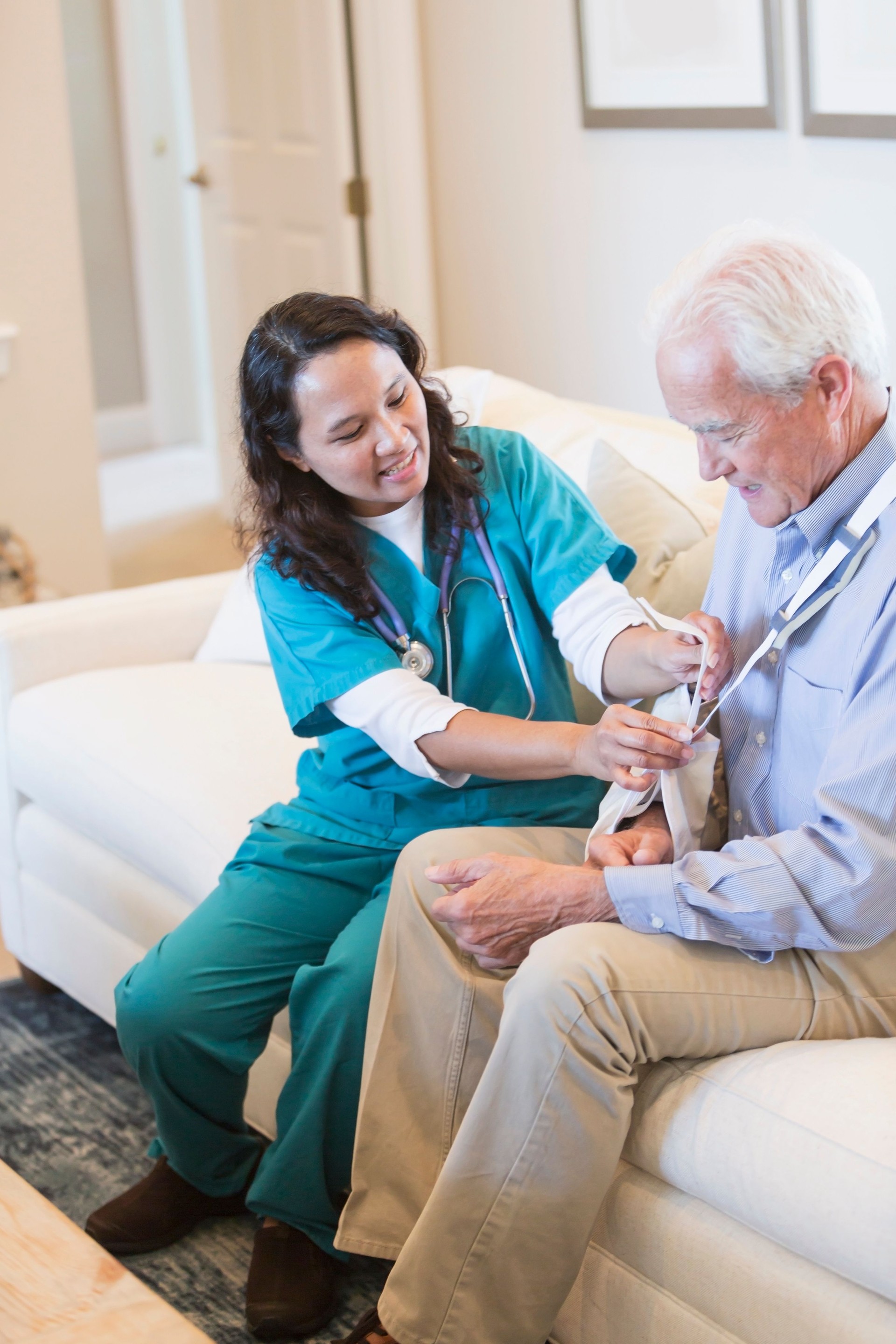 Home healthcare nurse helping senior man with sling